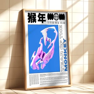 Framed “Year of the Monkey” poster leaning against a light wood cabinet, featuring a bright magenta and electric blue monkey design with Chinese characters.