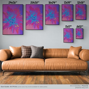 May include: A collection of abstract art prints showcasing a colourful floral design in pink, purple, and blue. The prints, ranging from 20.3cm x 30.5cm to 61cm x 91.4cm, are displayed above a brown leather sofa. The art is described as 'Art in transition'.