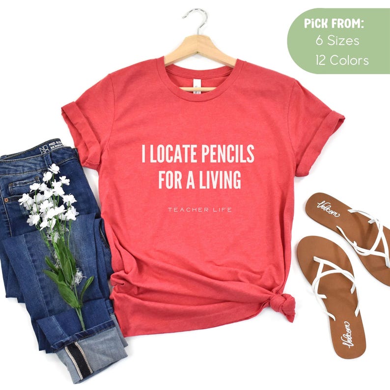 May include: Red short-sleeved t-shirt with the text "I locate pencils for a living" and "Teacher Life" in white.