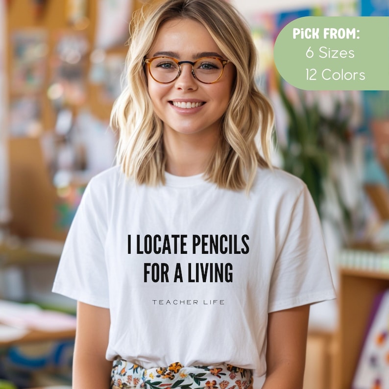 May include: White t-shirt with black text that reads "I locate pencils for a living" and "Teacher Life".