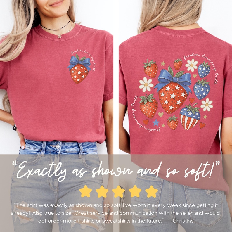 May include: Red t-shirt with a patriotic strawberry design. The front features a strawberry with a blue bow and stars, and the back has a larger design with strawberries, stars, and flowers. Text reads "freedom, democracy, truth."
