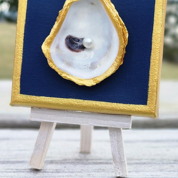 Handmade Oyster Shell mounted on 4" x 4" midnight blue and gold stretched canvas. Suitable for hanging or an easel. Easel not included.