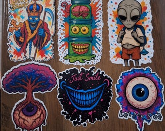 Puede incluir: Una colección de pegatinas coloridas con diseños únicos. Incluye un rey esqueleto, una pila de frascos con cerebros y ojos, un extraterrestre con una mochila, un árbol con un ojo, una boca sonriente con el texto "Just Smile" y un ojo con el texto "Let Me See".