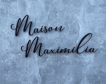 May include: A blue textured wall with the words "Maison Maximilia" written in black cursive script.