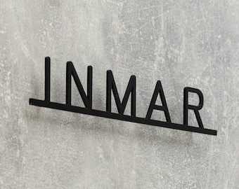 Puede incluir: Un letrero de metal negro con la palabra "INMAR" escrita en mayúsculas.