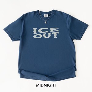 Puede incluir: Camiseta azul medianoche con el texto "ICE OUT" en una fuente gris claro desgastada. La camiseta tiene cuello redondo y mangas cortas. La palabra "MIDNIGHT" est&aacute; impresa en la parte inferior de la camiseta.