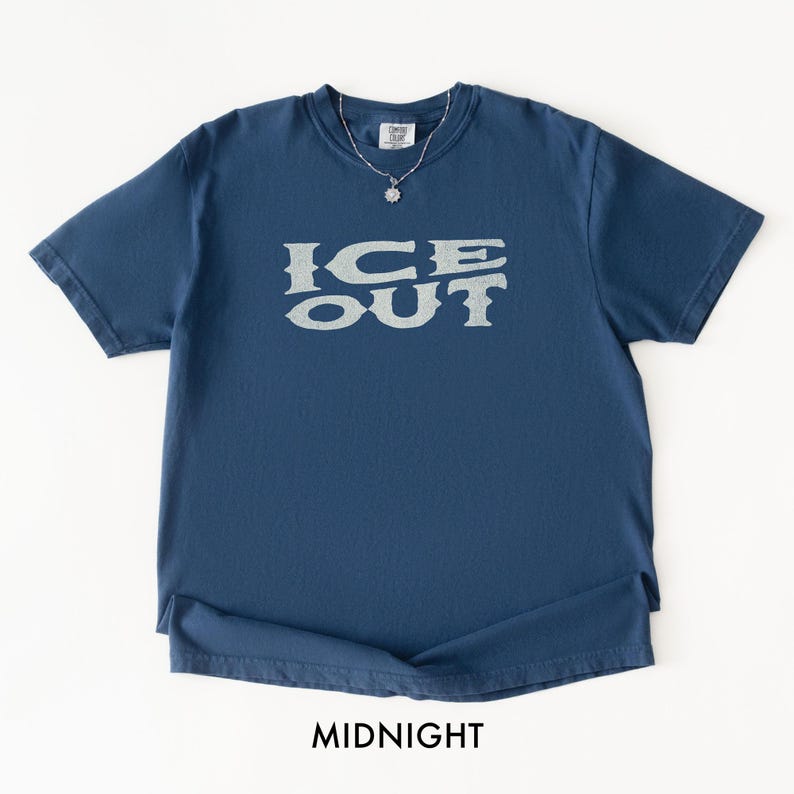 Puede incluir: Camiseta azul medianoche con el texto "ICE OUT" en una fuente gris claro desgastada. La camiseta tiene cuello redondo y mangas cortas. La palabra "MIDNIGHT" est&aacute; impresa en la parte inferior de la camiseta.