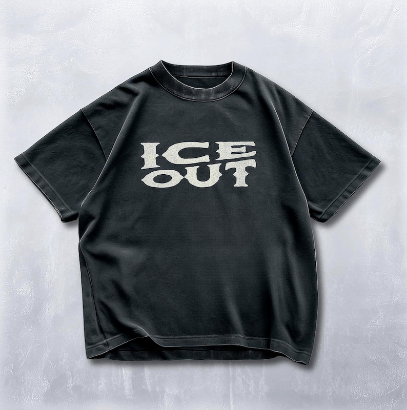 Puede incluir: Camiseta negra con el texto "ICE OUT" en una fuente estilizada de color crema. La camiseta tiene mangas cortas y cuello redondo. La tela parece ligeramente descolorida, d&aacute;ndole un aspecto vintage.