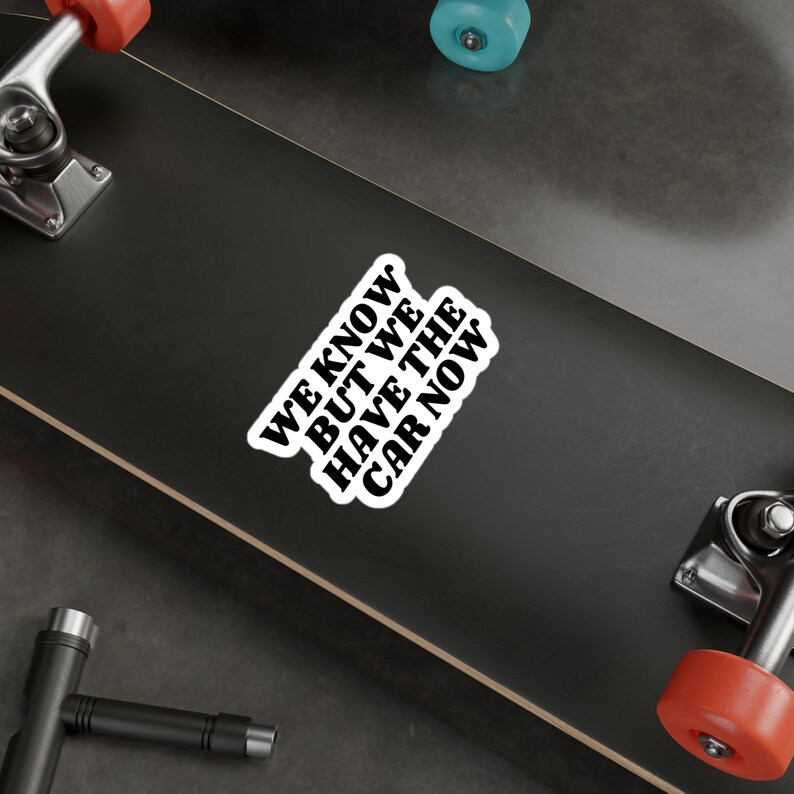 Op de afbeelding: Een zwart-witte sticker op een skateboard met de tekst "WE KNOW, BUT WE HAVE THE CAR NOW."