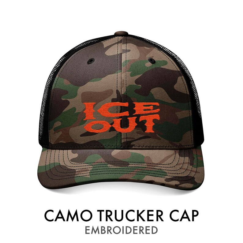 Puede incluir: Gorra de camionero camuflada con el texto "ICE OUT" bordado en naranja. La gorra presenta un patr&oacute;n de camuflaje en tonos verdes, marrones y negros, con una parte trasera de malla negra. Es una gorra de estilo camionero cl&aacute;sico.