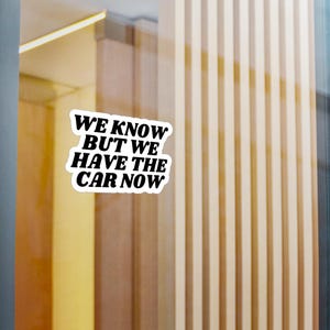 Op de afbeelding: Witte sticker met zwarte tekst die "We know but we have the car now" zegt.