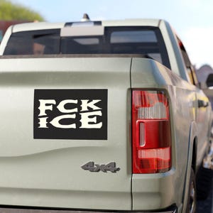 May include: A black rectangular bumper sticker with the words "FCK ICE" in a stylized, off-white font is affixed to the back of a light green pickup truck. The truck also has a "4x4" emblem.