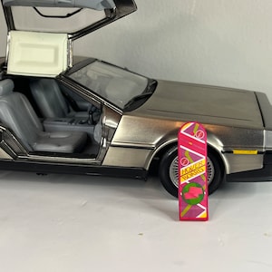 May include: A silver toy car with the doors open, revealing the interior. A pink and purple hoverboard with the text "Hover Board" is in front of the car.
