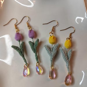 May include: A pair of crocheted flower earrings with pink and yellow flowers and iridescent teardrop beads.