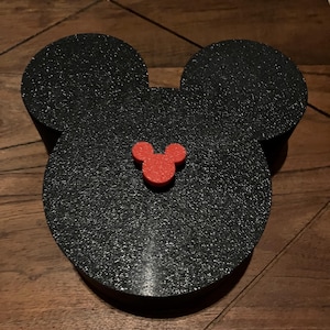 K&ouml;nnte beinhalten: Schwarze Mickey-Maus-Kopf-f&ouml;rmige Box mit einem roten Mickey-Maus-Kopf auf der Vorderseite.