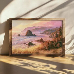 Puede incluir: Una pintura de paisaje rectangular en un marco de madera oscura que representa una escena costera al atardecer. La obra muestra hierbas doradas en primer plano, grandes formaciones rocosas en el océano y un cielo brumoso rosado y naranja.