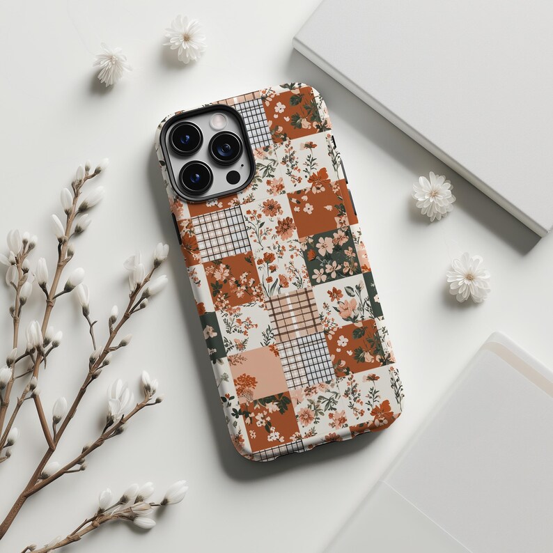 May include: A phone case with a patchwork design featuring floral and geometric patterns in shades of brown, white, and green.