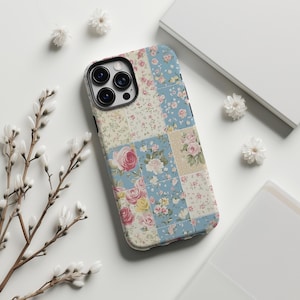 Peut inclure: Une coque de téléphone bleue et blanche avec un motif de patchwork floral. La coque a un découpage pour l'appareil photo et un motif floral.