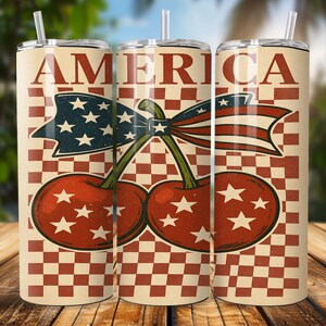 Op de afbeelding: Drie geïsoleerde bekers met een patriottisch ontwerp. Elke beker heeft het woord "AMERICA" in grote rode letters, een rood-witte geruite achtergrond en een afbeelding van kersen met een lint in de kleuren van de Amerikaanse vlag.