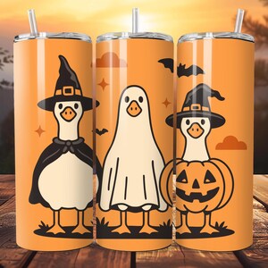 Op de afbeelding: Drie oranje Halloween-thema bekers met illustraties van ganzen in kostuums. Eén gans is verkleed als heks, een andere als spook en de derde als pompoen. Elke beker heeft een zilveren deksel en een rietje.