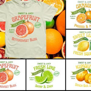 Op de afbeelding: Een lichtgekleurd t-shirt met een grapefruitontwerp, omringd door verse citrusvruchten. Het shirt heeft de tekst "Sweet & Juicy Grapefruit" en "Bittersweet Bliss". Andere ontwerpen zijn onder meer sinaasappels, citroenen, limoenen en kumquats.