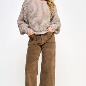 K&ouml;nnte beinhalten: Ein hellbrauner Strickpullover mit Rundhalsausschnitt und langen &Auml;rmeln. Der Pullover hat eine leicht verk&uuml;rzte L&auml;nge und eine lockere Passform.