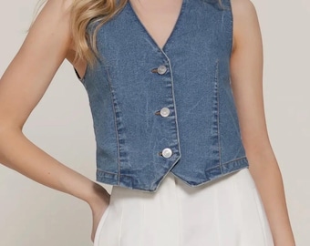 May include: A sleeveless denim vest in a light blue wash. The vest features a V-neckline, a button-up front with three white buttons, and a tailored fit. The vest is a classic piece of apparel.