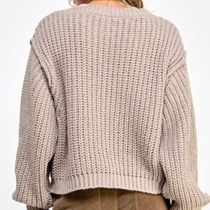 K&ouml;nnte beinhalten: Ein hellbrauner Strickpullover mit lockerer Passform und langen &Auml;rmeln. Der Pullover hat eine gerippte Struktur und einen leicht verk&uuml;rzten Saum.