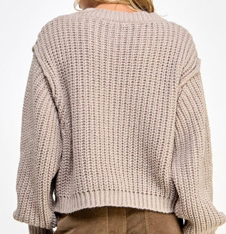 K&ouml;nnte beinhalten: Ein hellbrauner Strickpullover mit lockerer Passform und langen &Auml;rmeln. Der Pullover hat eine gerippte Struktur und einen leicht verk&uuml;rzten Saum.