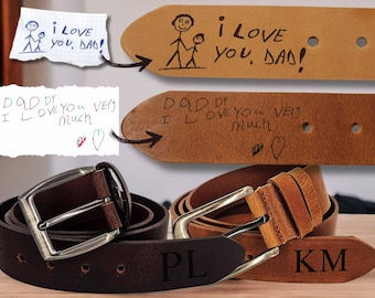 Puede incluir: Dos cinturones de cuero marrón con grabados personalizados. Un cinturón tiene las iniciales "PL" y el otro las iniciales "KM". Ambos cinturones tienen mensajes escritos a mano, uno dice "Daddy I love you very much" y el otro dice "I love you, Dad!"