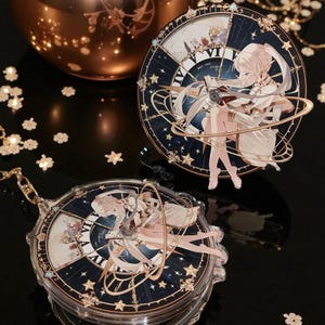 May include: Two decorative clock-themed acrylic charms. Each charm features a celestial design with a seated anime-style character. The clocks have a dark blue background with gold accents and star details. One charm is a keychain.