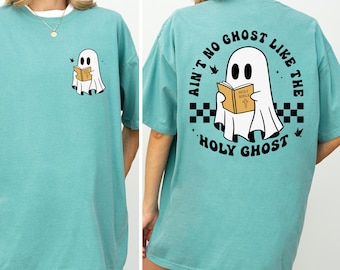 Op de afbeelding: Een turquoise T-shirt met korte mouwen met een cartoongeest die een boek leest. De voorkant van het shirt heeft een kleine spookafbeelding. De achterkant van het shirt heeft een grotere afbeelding met de tekst "Ain't No Ghost Like The Holy Ghost."