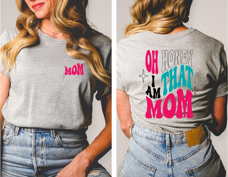 Puede incluir: Una camiseta gris con la palabra "MOM" en rosa en la parte delantera y el texto "OH HONEY I AM THAT MOM" en rosa, negro y turquesa en la parte trasera.