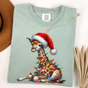 Comfort Colors® Cute Christmas Giraffe Lights Shirt, Funny Holiday Animal Tee, Festive Lights Giraffe Hat Santa Gift Shirt, Xmas Giraffe Tee