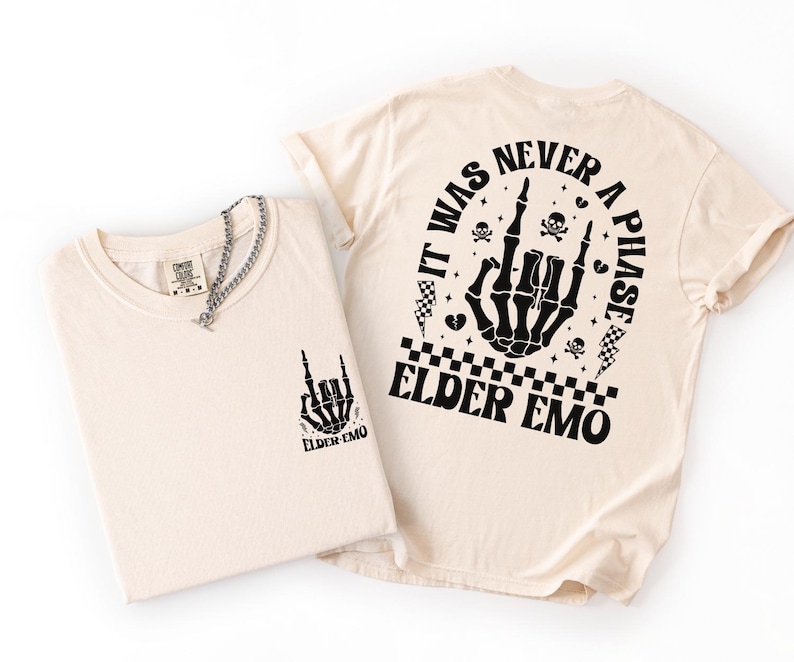 K&ouml;nnte beinhalten: Zwei cremefarbene T-Shirts mit schwarzen Grafikdesigns. Ein Shirt zeigt eine Skeletthand mit dem Text "ELDER EMO". Das andere Shirt hat ein gr&ouml;&szlig;eres Design auf dem R&uuml;cken mit dem Text "IT WAS NEVER A PHASE ELDER EMO". Eine silberne Halskette befindet sich auf einem Shirt.