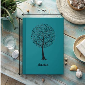 Könnte beinhalten: Ein türkisfarbenes Notizbuch mit einem schwarzen Musiknotenbaum-Design und dem Namen "Austin" auf der Vorderseite. Das Notizbuch misst 20,3 cm x 14,6 cm.