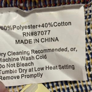 May include: A white tag with black text indicating the composition of a textile: 60% Polyester and 40% Cotton. The tag also states "MADE IN CHINA" and care instructions: dry cleaning or machine wash cold.