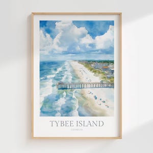 May include: Watercolor print of Tybee Island, Georgia, featuring a beach, pier, and ocean under a cloudy blue sky. The artwork is framed in a light wood frame. The text "Tybee Island Georgia" is printed at the bottom of the image.