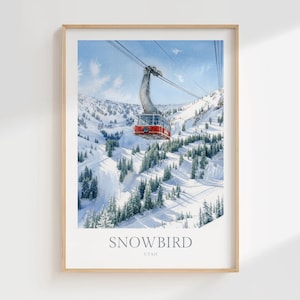 May include: A framed art print featuring a watercolor illustration of a red aerial tram car suspended by cables over a snow-covered mountain landscape with evergreen trees. The text SNOWBIRD UTAH is printed in a grey serif font at the bottom.