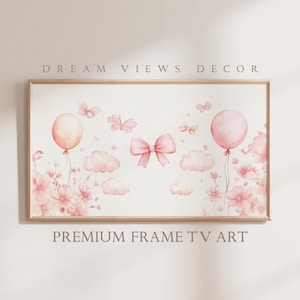 Peut inclure: Une impression aquarelle encadrée représentant des ballons roses, des papillons, des nuages et un nœud. L'impression a un fond blanc et est entourée d'un cadre brun clair. Le texte "DREAM VIEWS DECOR" est en haut de l'image et "PREMIUM FRAME TV ART" est en bas.
