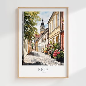 Puede incluir: Una pintura de acuarela de una calle estrecha en Riga, Letonia. La calle está bordeada de edificios coloridos y tiene una superficie de adoquines. Hay flores en macetas a los lados de la calle. La pintura está enmarcada en un marco de madera claro.