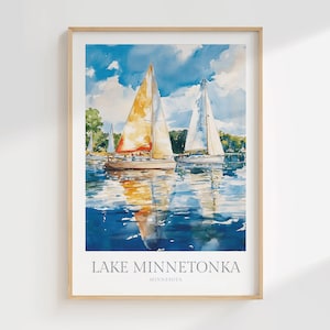 May include: A framed watercolor art print featuring two sailboats on blue water under a cloudy sky. The primary sailboat has a large orange and yellow sail. The text at the bottom reads LAKE MINNETONKA MINNESOTA in a clean, sans-serif font.