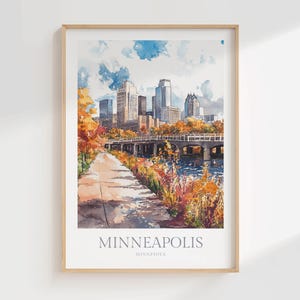 May include: A framed watercolor art print of the Minneapolis, Minnesota skyline featuring a city bridge over water, a paved path, and autumn foliage in shades of orange and yellow under a blue sky with clouds. The text reads MINNEAPOLIS MINNESOTA.