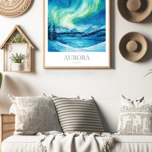 May include: A watercolor painting of the aurora borealis over a snowy landscape. The painting is framed in a light wood frame and has the text "AURORA ICELAND" at the bottom.