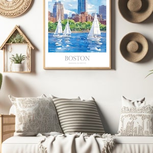 May include: A watercolor painting of the Boston skyline with sailboats in the foreground. The painting is framed in a light wood frame and is hanging on a white wall. The text "BOSTON MASSACHUSETTS" is printed below the image.