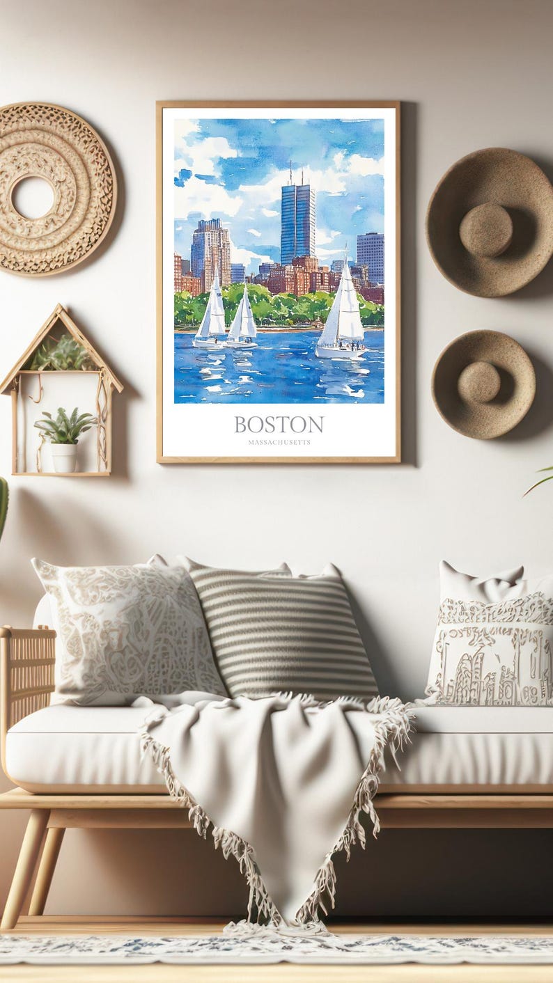 May include: A watercolor painting of the Boston skyline with sailboats in the foreground. The painting is framed in a light wood frame and is hanging on a white wall. The text "BOSTON MASSACHUSETTS" is printed below the image.