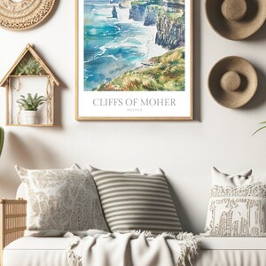 May include: A watercolour painting of the Cliffs of Moher in Ireland. The painting depicts the cliffs rising up from the sea, with waves crashing against the rocks. The sky is a light blue, with some clouds. The painting is framed in a wooden frame.