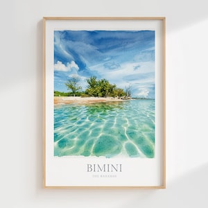 May include: A framed wall art print featuring a watercolor-style landscape of a tropical beach in Bimini, The Bahamas. The image displays clear turquoise water with light reflections, a sandy shoreline, green trees, and a bright blue sky.