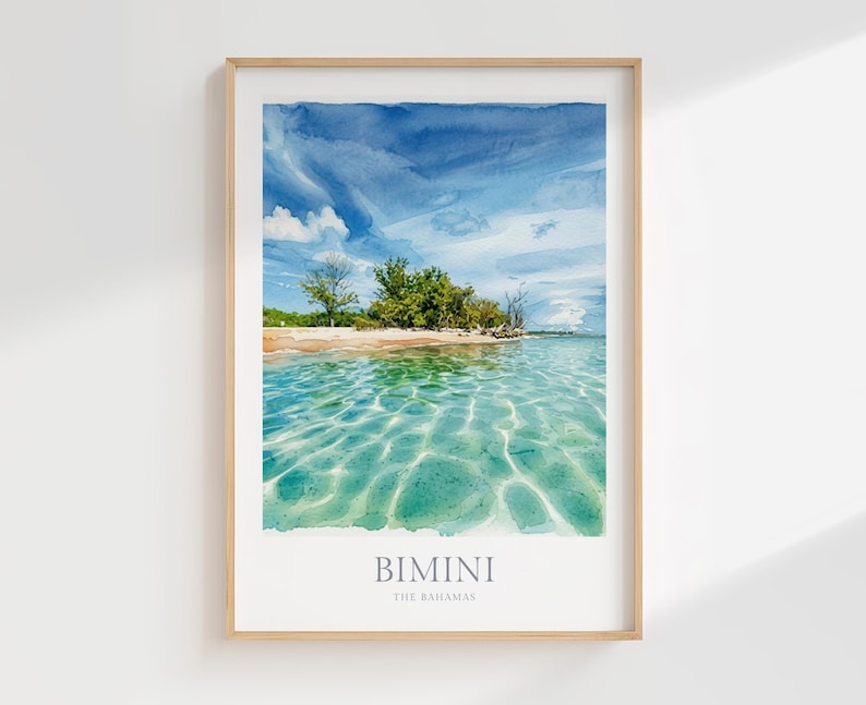 May include: A framed wall art print featuring a watercolor-style landscape of a tropical beach in Bimini, The Bahamas. The image displays clear turquoise water with light reflections, a sandy shoreline, green trees, and a bright blue sky.