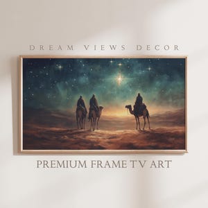 Könnte beinhalten: Gerahmter Kunstdruck, der drei Figuren auf Kamelen vor einem sternenklaren Nachthimmel zeigt. Das Kunstwerk verwendet eine warme Farbpalette mit einem hellen Stern in der Mitte. Der Text "DREAM VIEWS DECOR" und "PREMIUM FRAME TV ART" sind zu sehen.